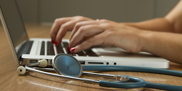 Datenschutz im Gesundheitswesen – Kachel Laptop und Stethoskop auf einem Schreibtisch
