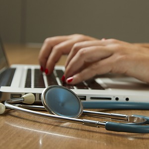 Laptop und Stethoskop auf einem Schreibtisch